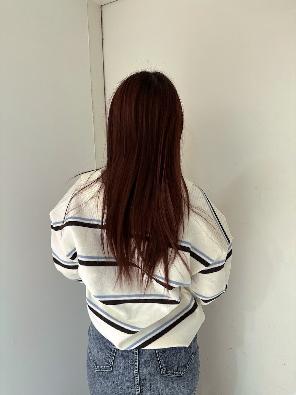 ブラック系のブーツ、ホワイト系のニット/セーター、ブルー系のデニムスカートを着用したレディースの冬コーディネートの6枚目の写真