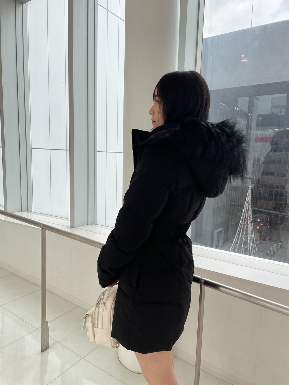 ブラック系のダウンジャケット/コート、ブラック系のワンピース、ホワイト系のバックパック/リュックを着用したレディースの冬コーディネートの5枚目の写真