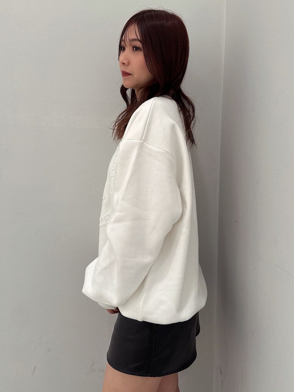 ブラック系のスカート、ブラック系のブーツ、ホワイト系のスウェットを着用したレディースの冬コーディネートの5枚目の写真