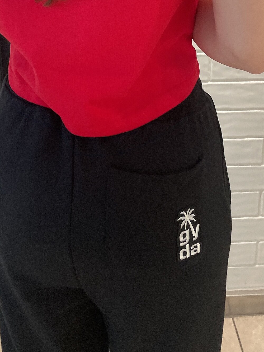 レッド系のTシャツ/カットソー、ブラック系のスウェットパンツ、ホワイト系のスニーカーを着用したレディースの夏コーディネートの6枚目の写真