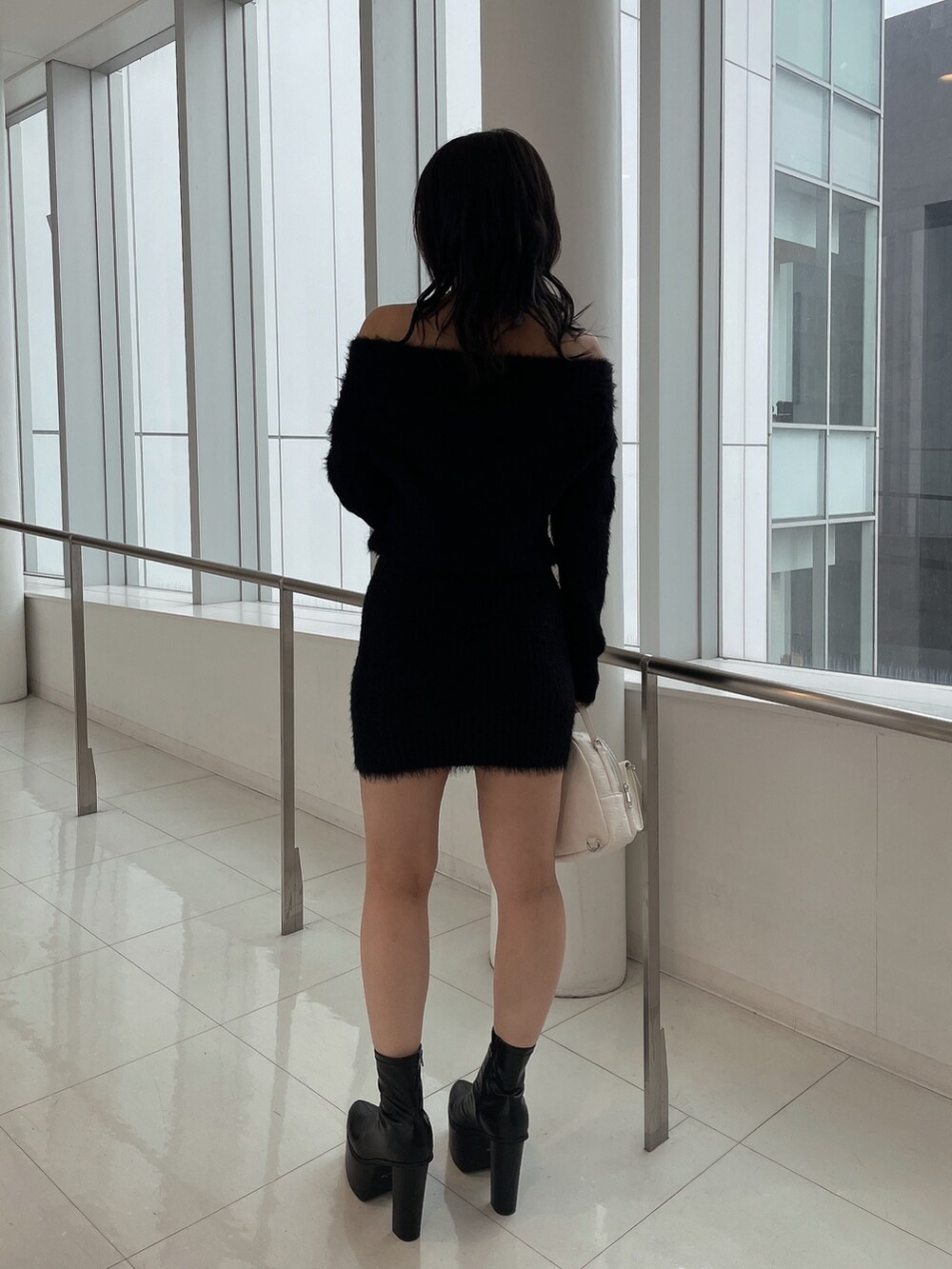 ブラック系のダウンジャケット/コート、ブラック系のワンピース、ホワイト系のバックパック/リュックを着用したレディースの冬コーディネートの8枚目の写真