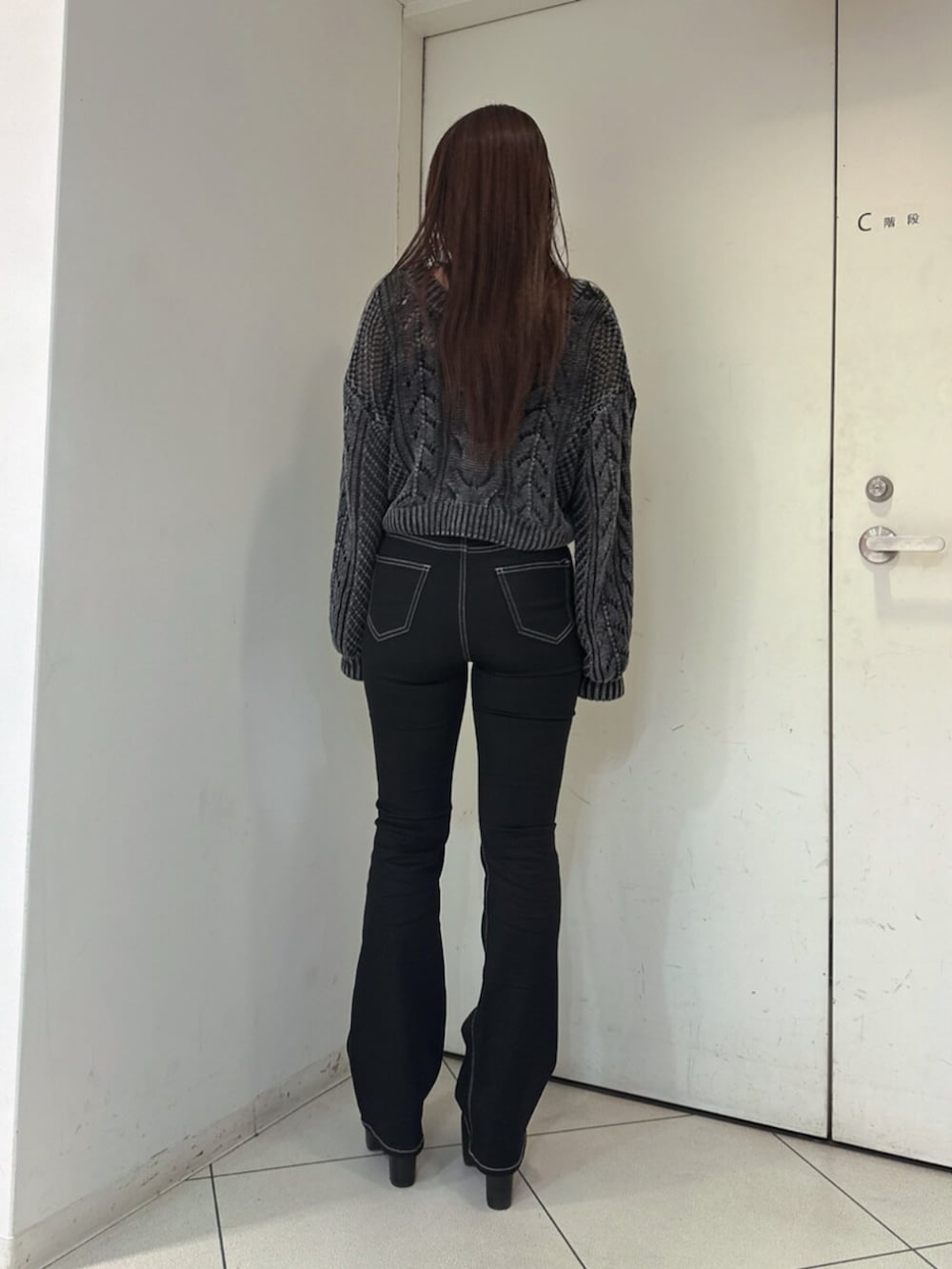 ブラック系のデニムパンツ、ブラック系のブーツ、ブラック系のニット/セーターを着用したレディースの夏コーディネートの3枚目の写真