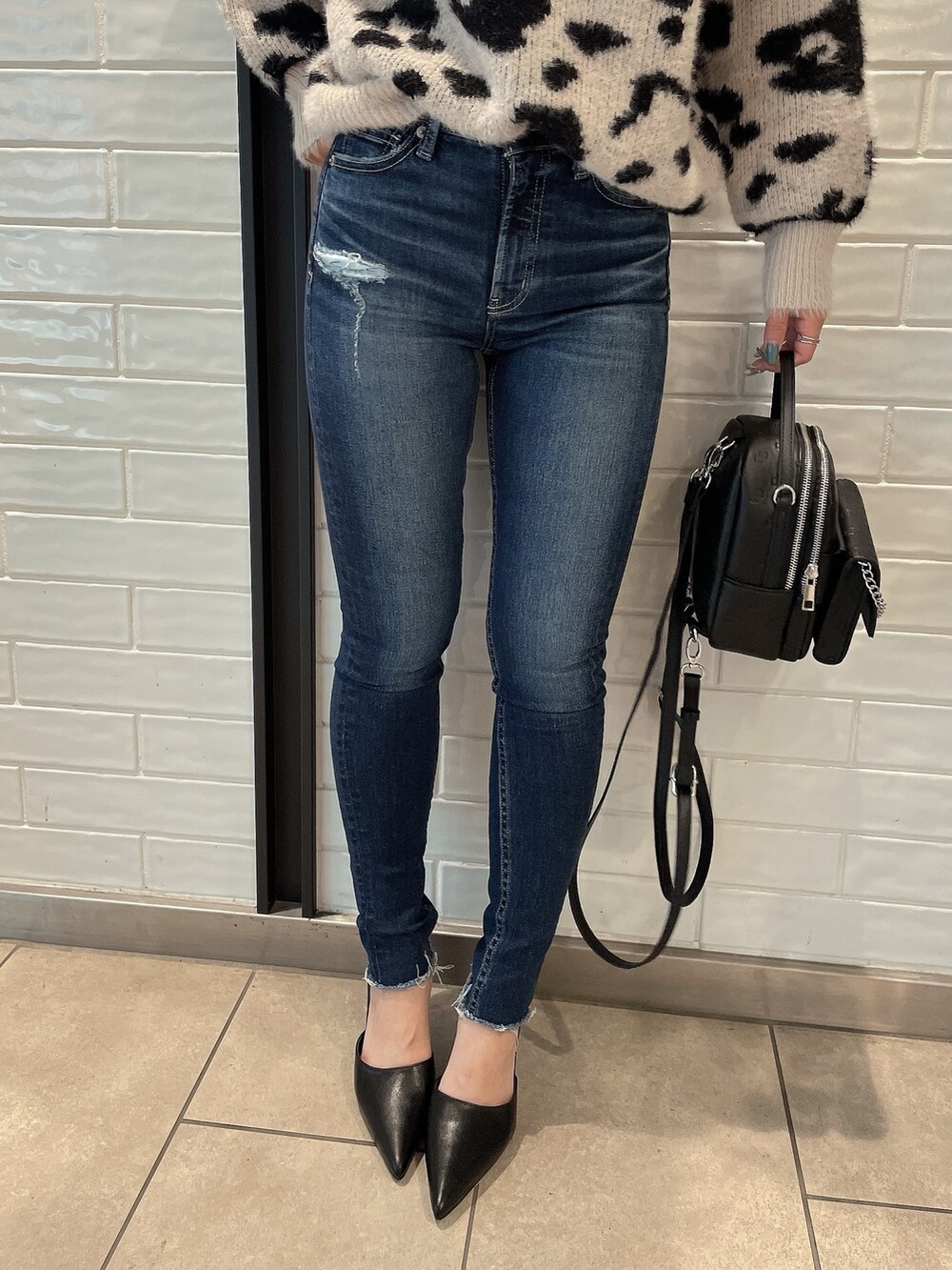 ホワイト系のニット/セーター、ブラック系のバックパック/リュック、ブラック系のパンプスを着用したレディースの冬コーディネートの6枚目の写真