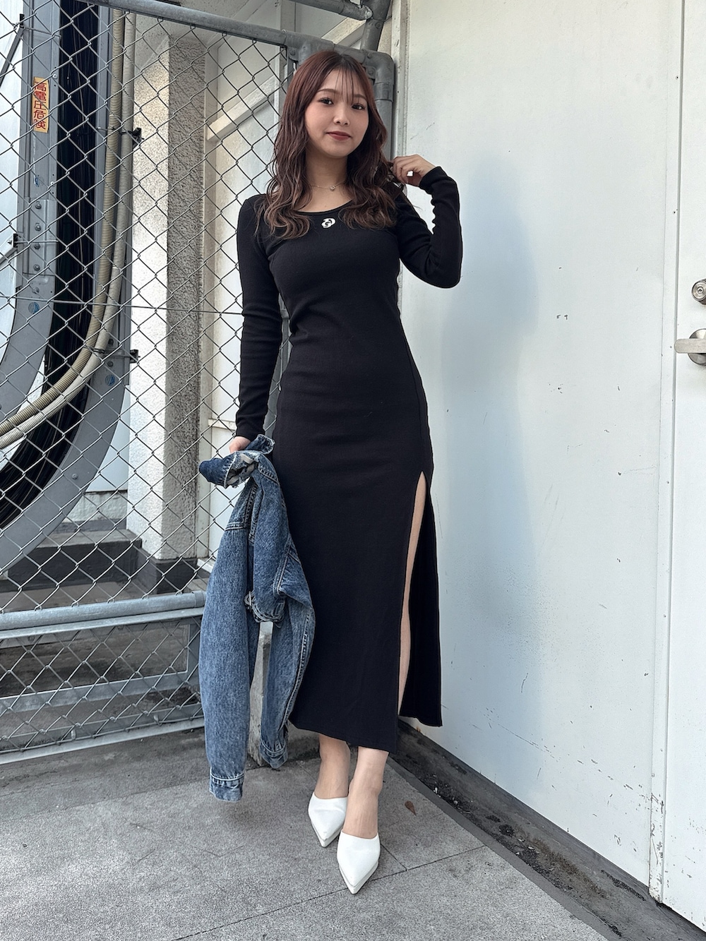 ブラック系のワンピース、ホワイト系のパンプス、ブルー系のデニムジャケットを着用したレディースの春コーディネートの4枚目の写真