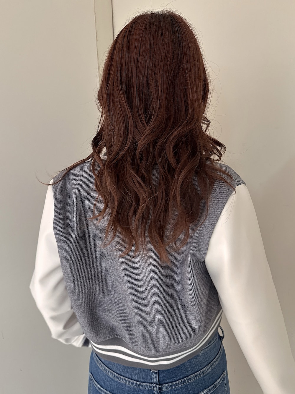 グレー系のニット/セーター、ブルー系のデニムパンツ、ホワイト系のパンプスを着用したレディースの冬コーディネートの6枚目の写真