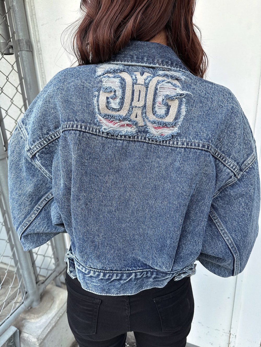 ブラック系のワンピース、ホワイト系のパンプス、ブルー系のデニムジャケットを着用したレディースの春コーディネートの7枚目の写真