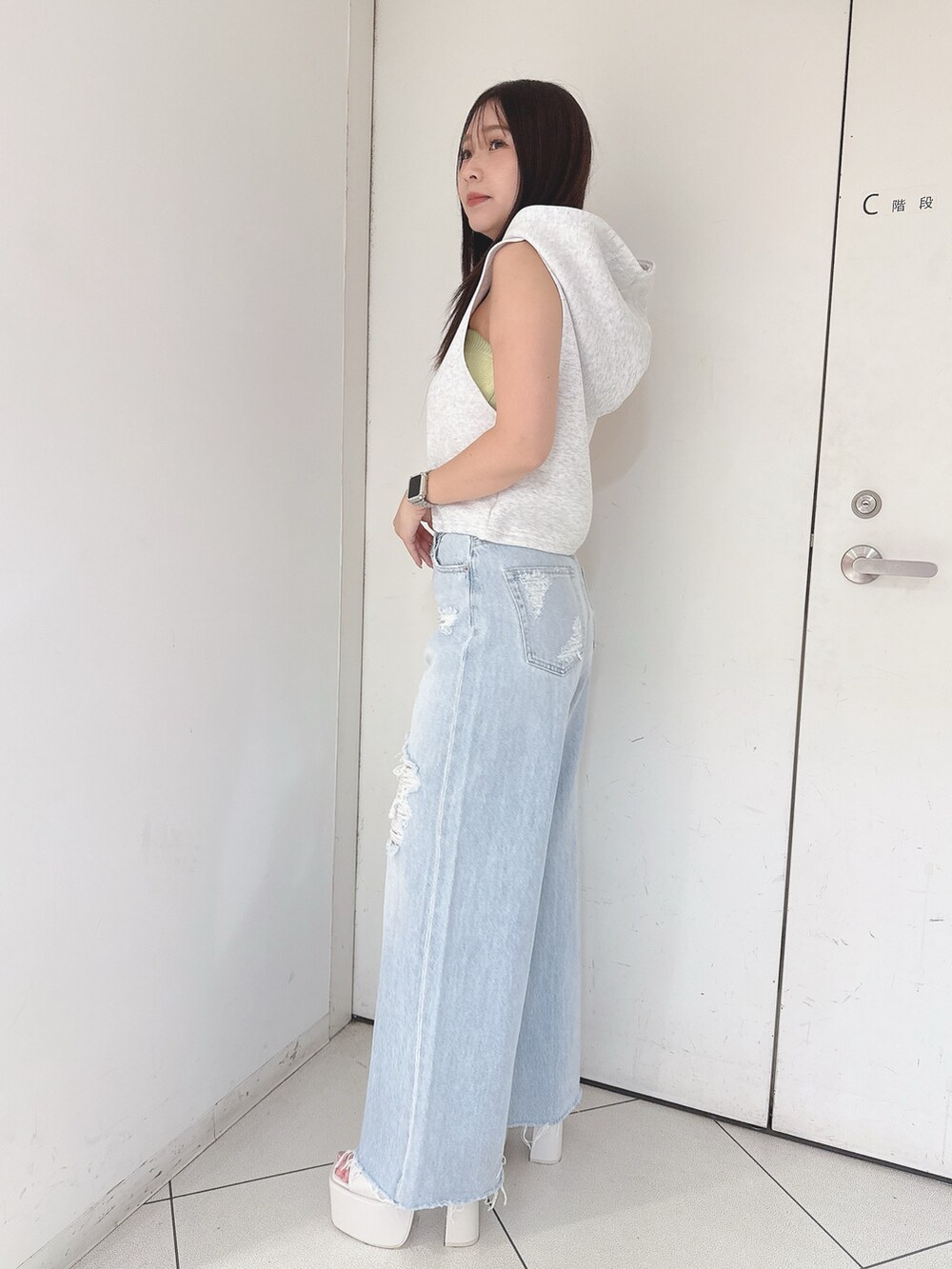 グレー系のパーカー、ブルー系のデニムパンツ、ホワイト系のサンダルを着用したレディースの夏コーディネートの2枚目の写真