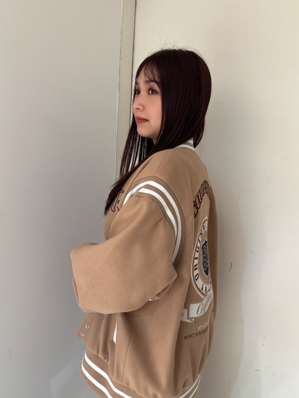 ブラック系のデニムパンツ、ブラック系のニット/セーター、ベージュ系のスタジャンを着用したレディースの秋コーディネートの5枚目の写真