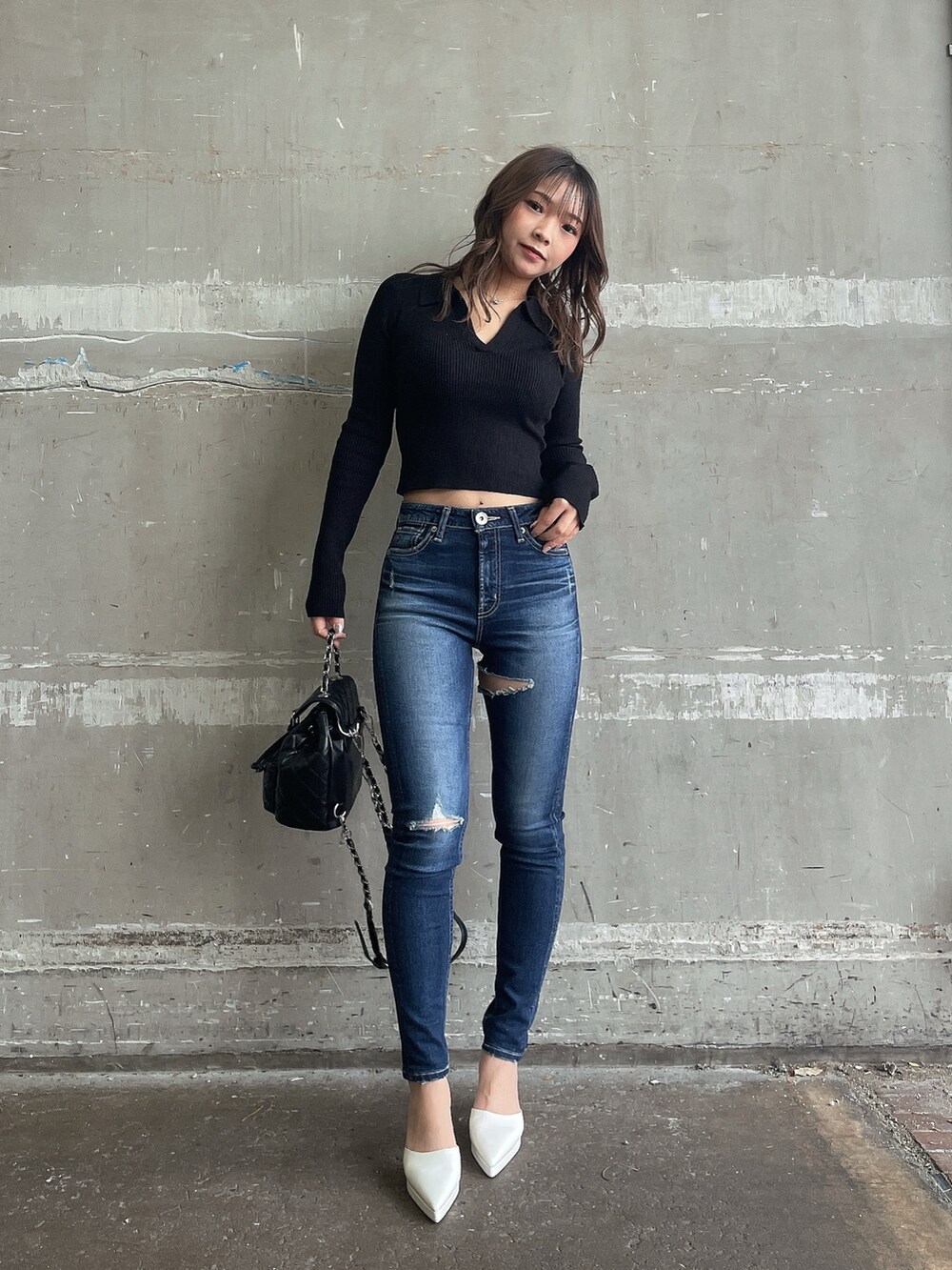 ブラック系のニット/セーター、ブラック系のチェスターコート、ブルー系のデニムパンツを着用したレディースの冬コーディネートの3枚目の写真