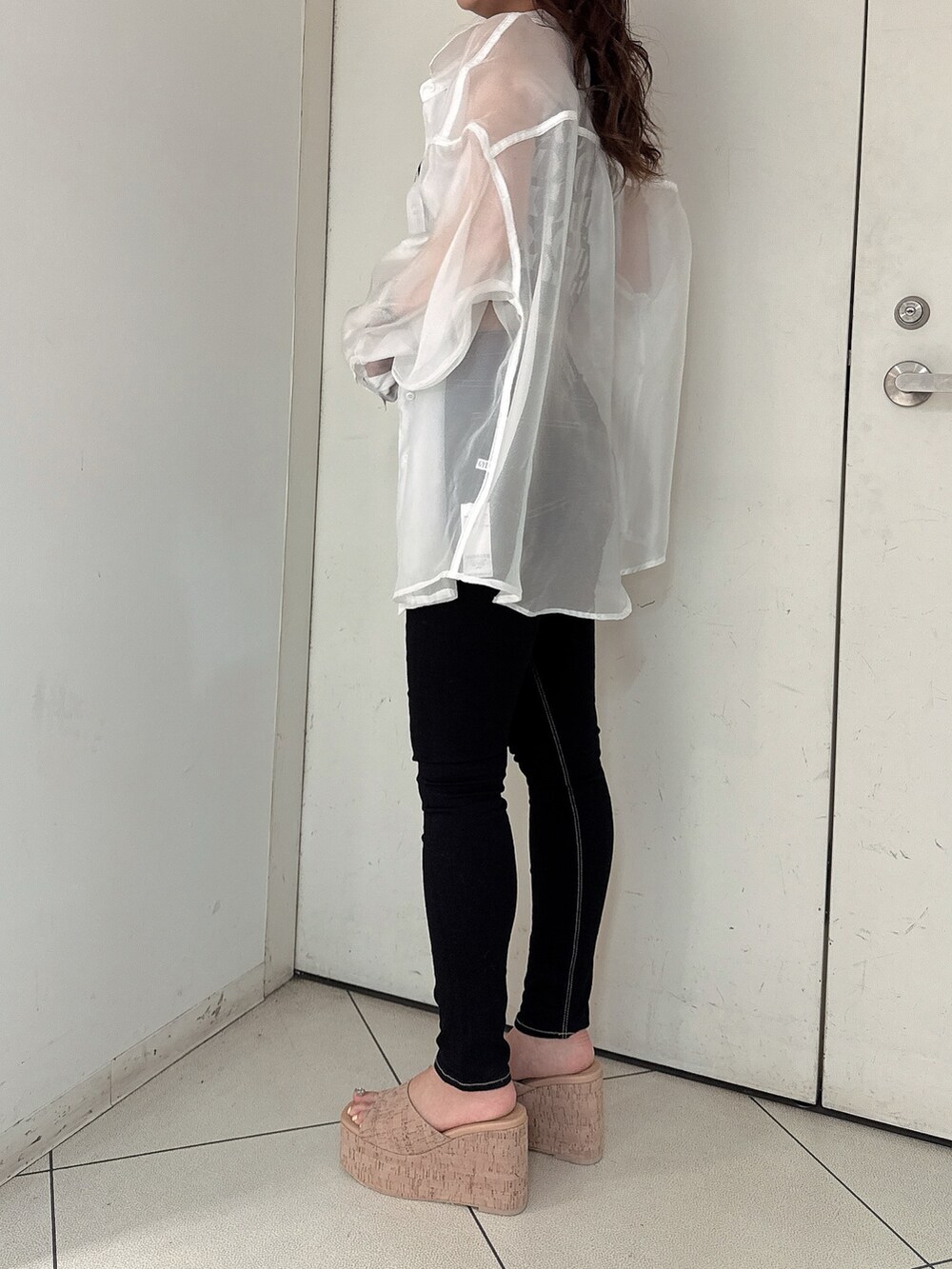 ブラック系のニット/セーター、ブラック系のデニムパンツ、ホワイト系のシャツ/ブラウスを着用したレディースの春コーディネートの2枚目の写真