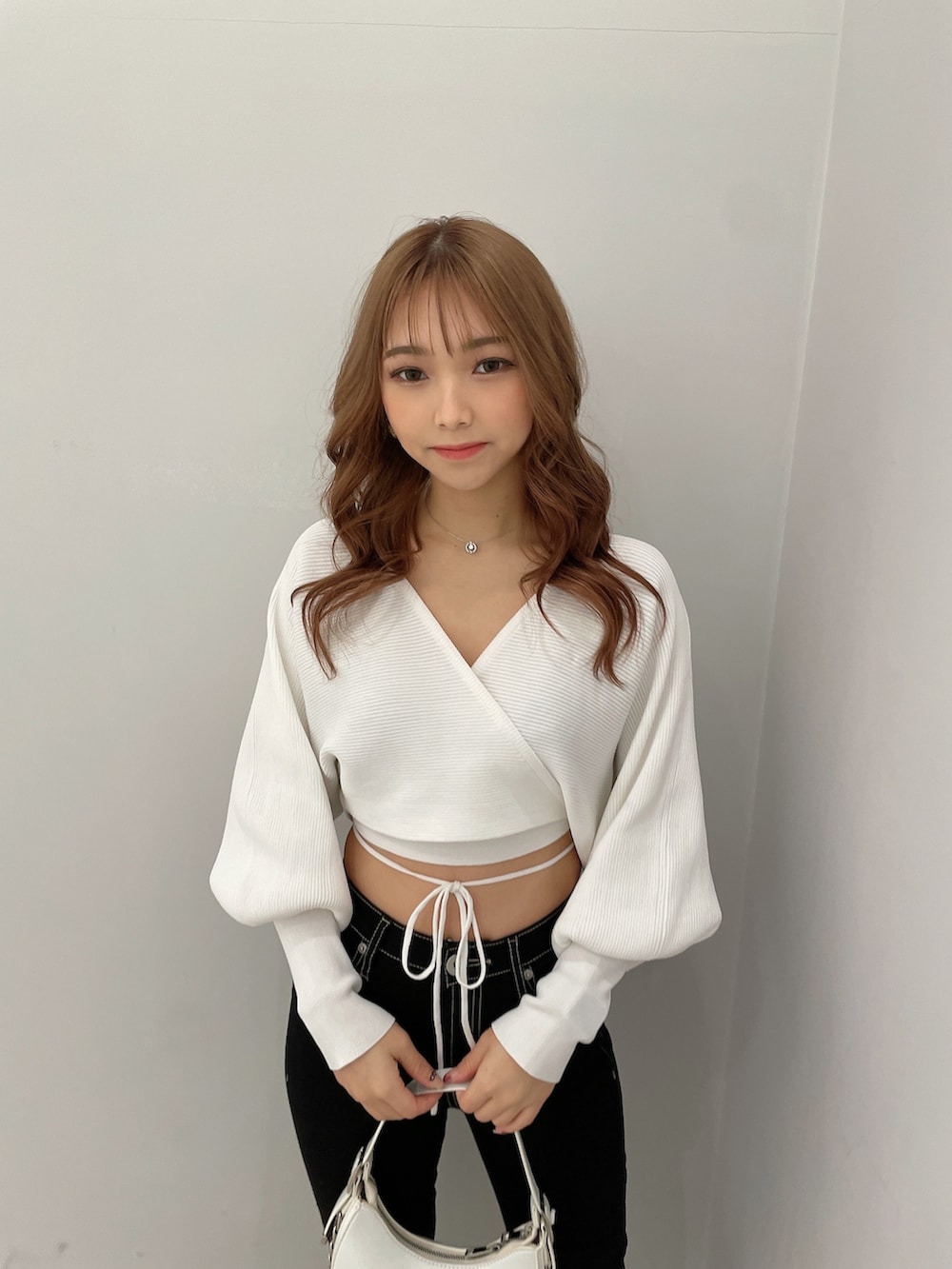 ブラック系のデニムパンツ、ブラック系のハンドバッグ、ホワイト系のパンプスを着用したレディースの春コーディネートの4枚目の写真