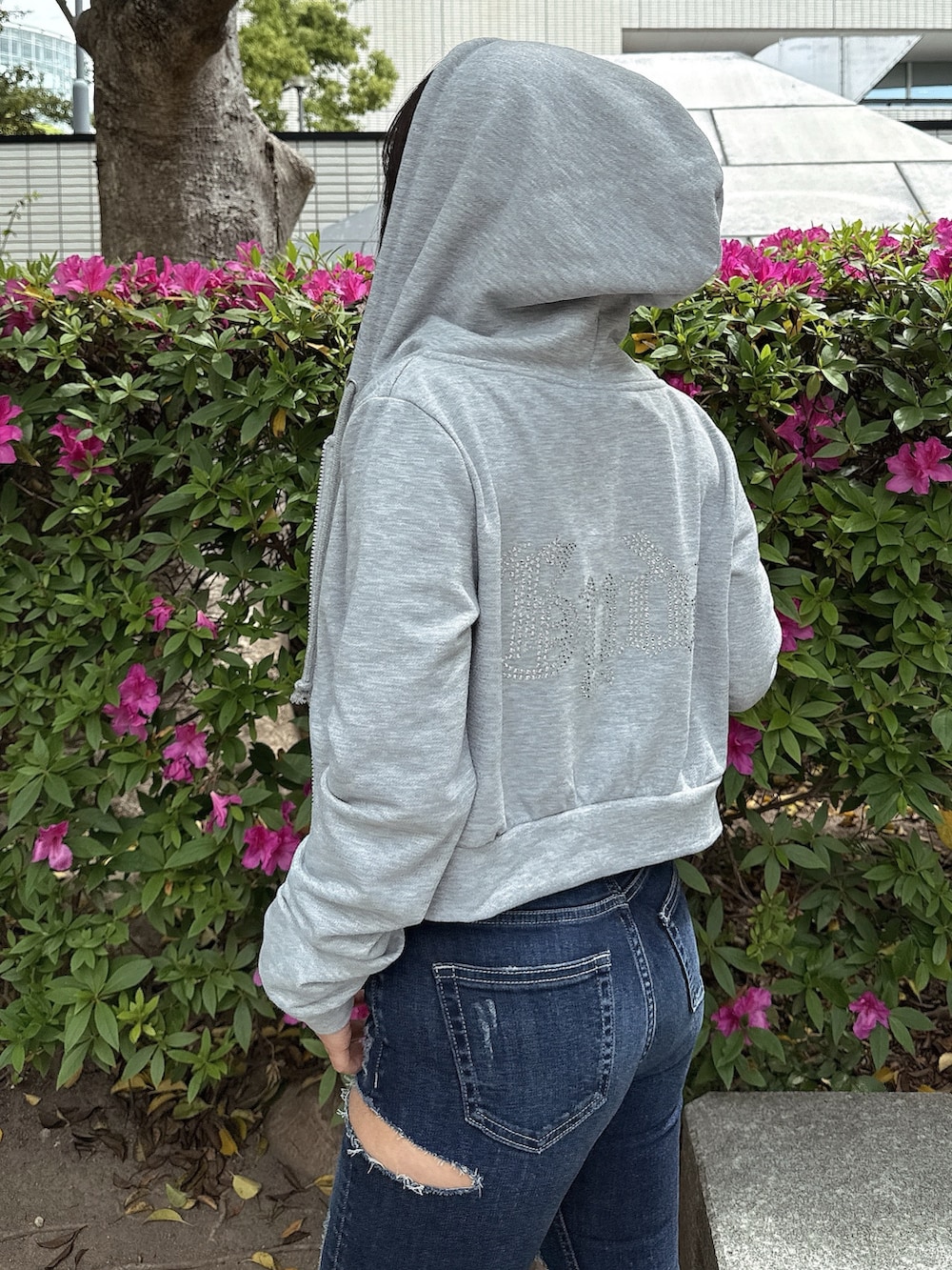 グレー系のパーカー、ブルー系のデニムパンツ、ホワイト系のサンダルを着用したレディースの春コーディネートの5枚目の写真