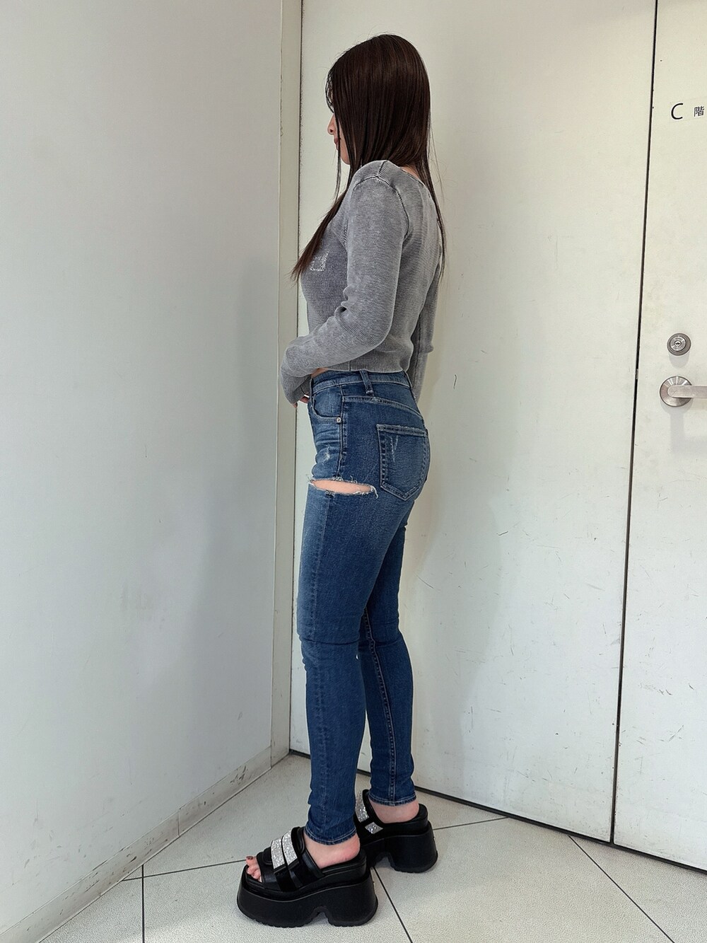 ブラック系のニット/セーター、ブルー系のデニムパンツ、ブラック系のサンダルを着用したレディースの春コーディネートの2枚目の写真