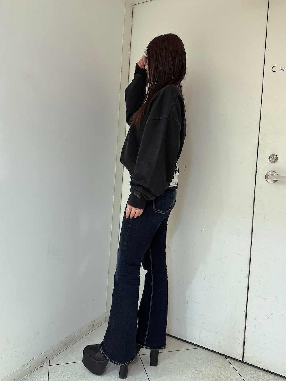 ブルー系のデニムパンツ、ブラック系のスウェット、ブラック系のブーツを着用したレディースの冬コーディネートの2枚目の写真