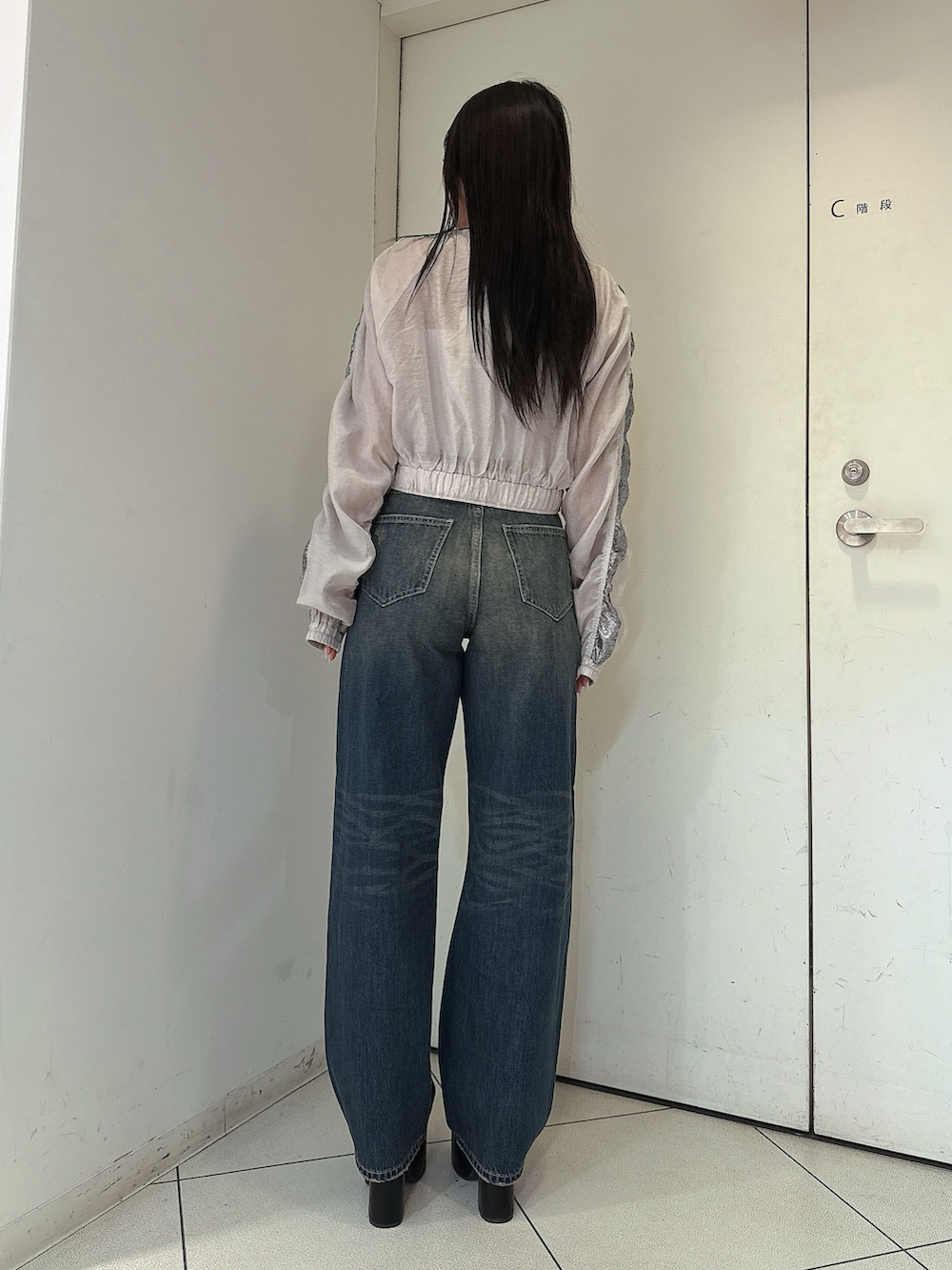 ブルー系のデニムパンツ、ホワイト系のキャミソール、ホワイト系のブルゾンを着用したレディースの春コーディネートの3枚目の写真