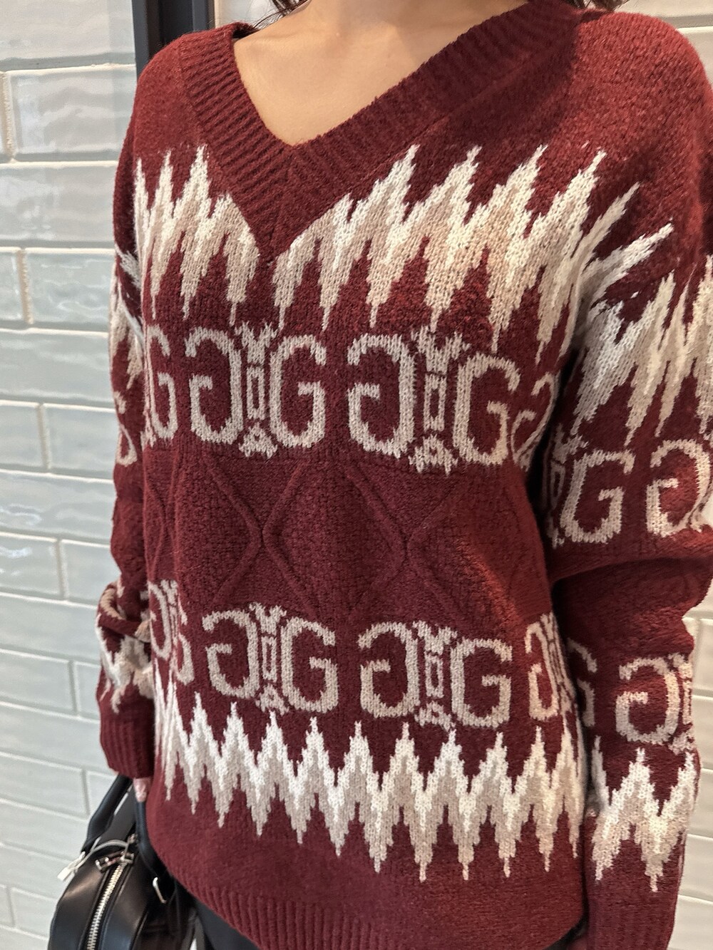 レッド系のニット/セーター、ブラック系のスカート、ブラック系のハンドバッグを着用したレディースの冬コーディネートの7枚目の写真