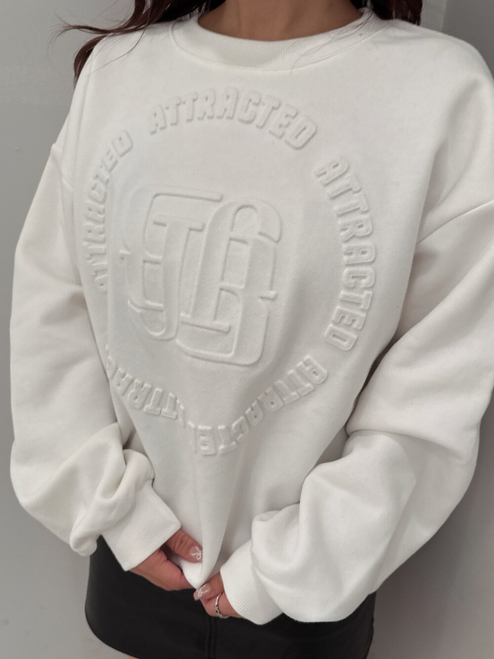 ブラック系のスカート、ブラック系のブーツ、ホワイト系のスウェットを着用したレディースの冬コーディネートの7枚目の写真