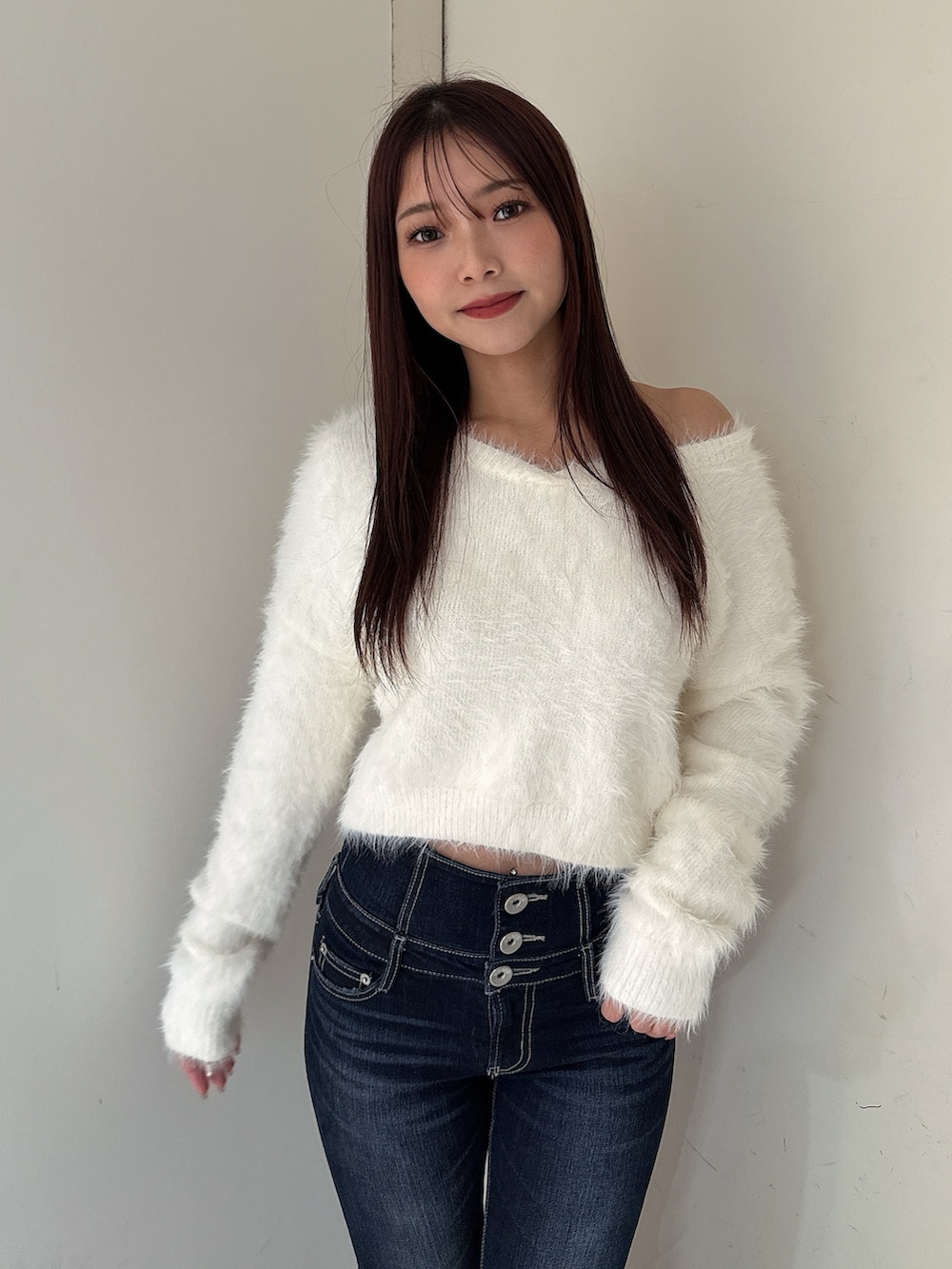 ブルー系のデニムパンツ、ブラック系のブーツ、ホワイト系のニット/セーターを着用したレディースの秋コーディネートの4枚目の写真