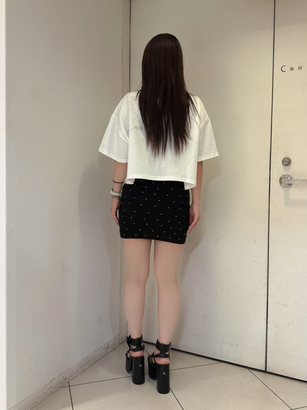 ブラック系のスカート、ホワイト系のTシャツ/カットソー、ブラック系のサンダルを着用したレディースの夏コーディネートの3枚目の写真