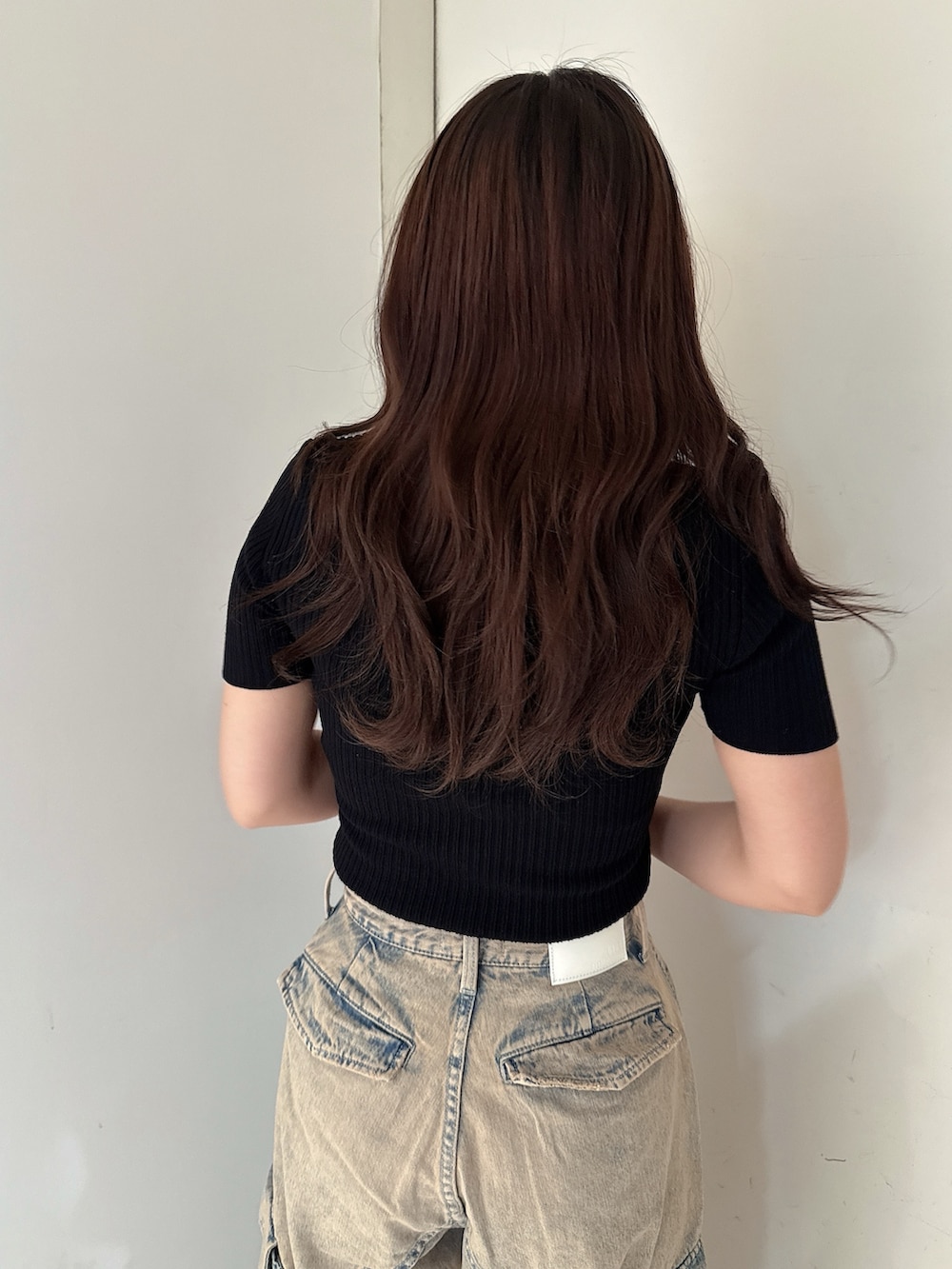 ブラック系のニット/セーター、ブルー系のデニムパンツ、ブラック系のサンダルを着用したレディースの夏コーディネートの6枚目の写真