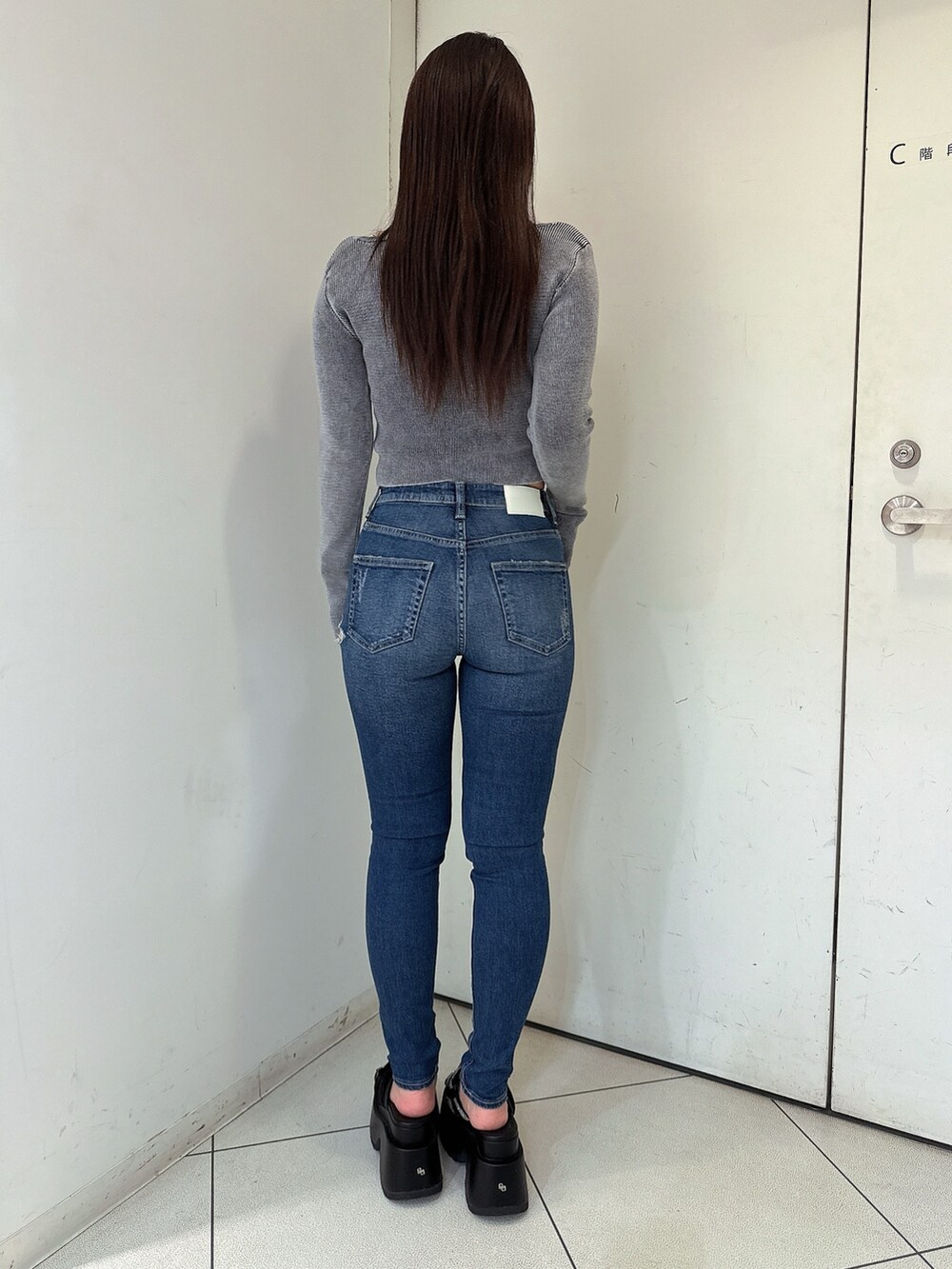 ブラック系のニット/セーター、ブルー系のデニムパンツ、ブラック系のサンダルを着用したレディースの春コーディネートの3枚目の写真