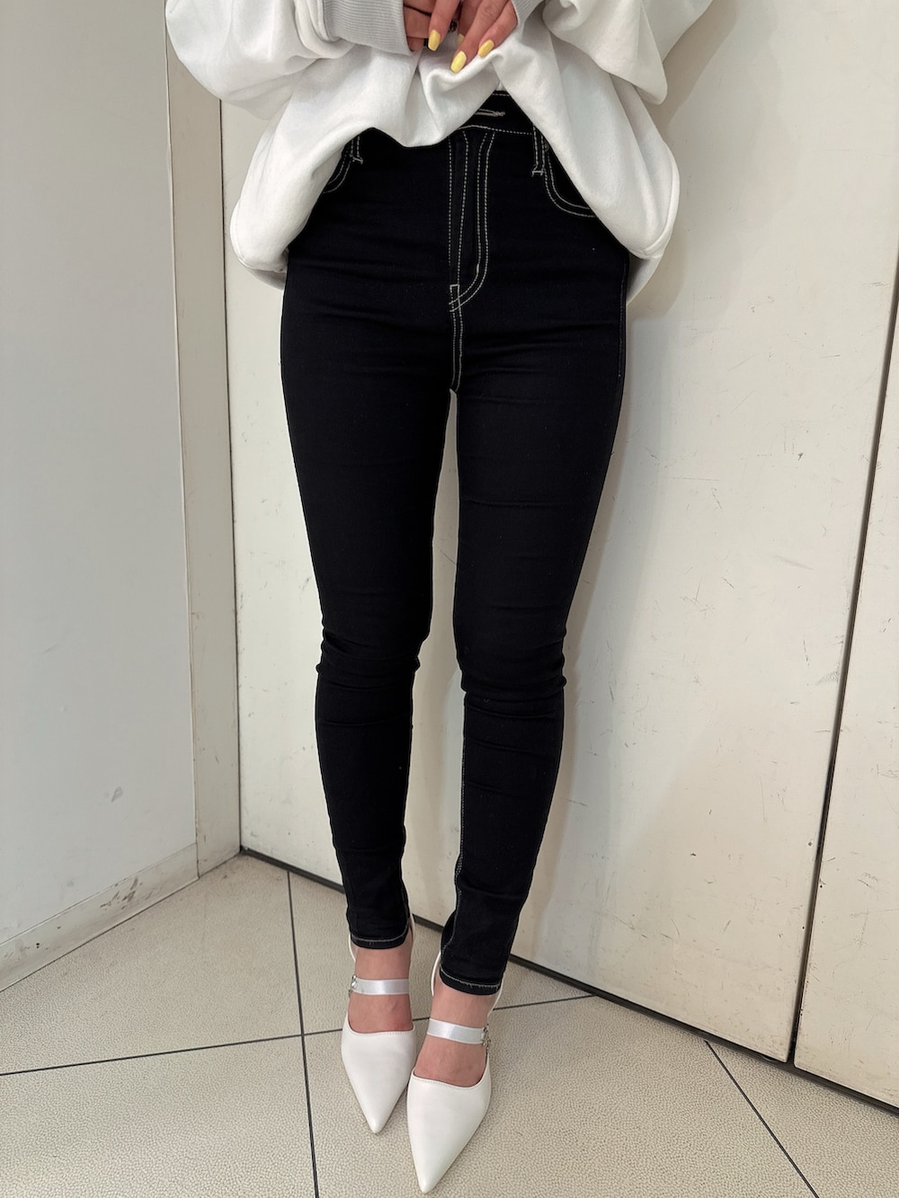 ブラック系のデニムパンツ、ホワイト系のスウェット、ホワイト系のパンプスを着用したレディースの冬コーディネートの9枚目の写真