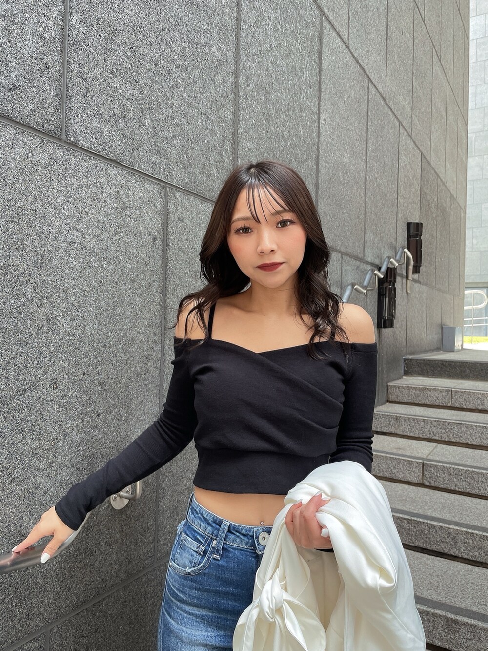 ホワイト系のトレンチコート、ブラック系のTシャツ/カットソー、ブルー系のデニムパンツを着用したレディースの春コーディネートの6枚目の写真