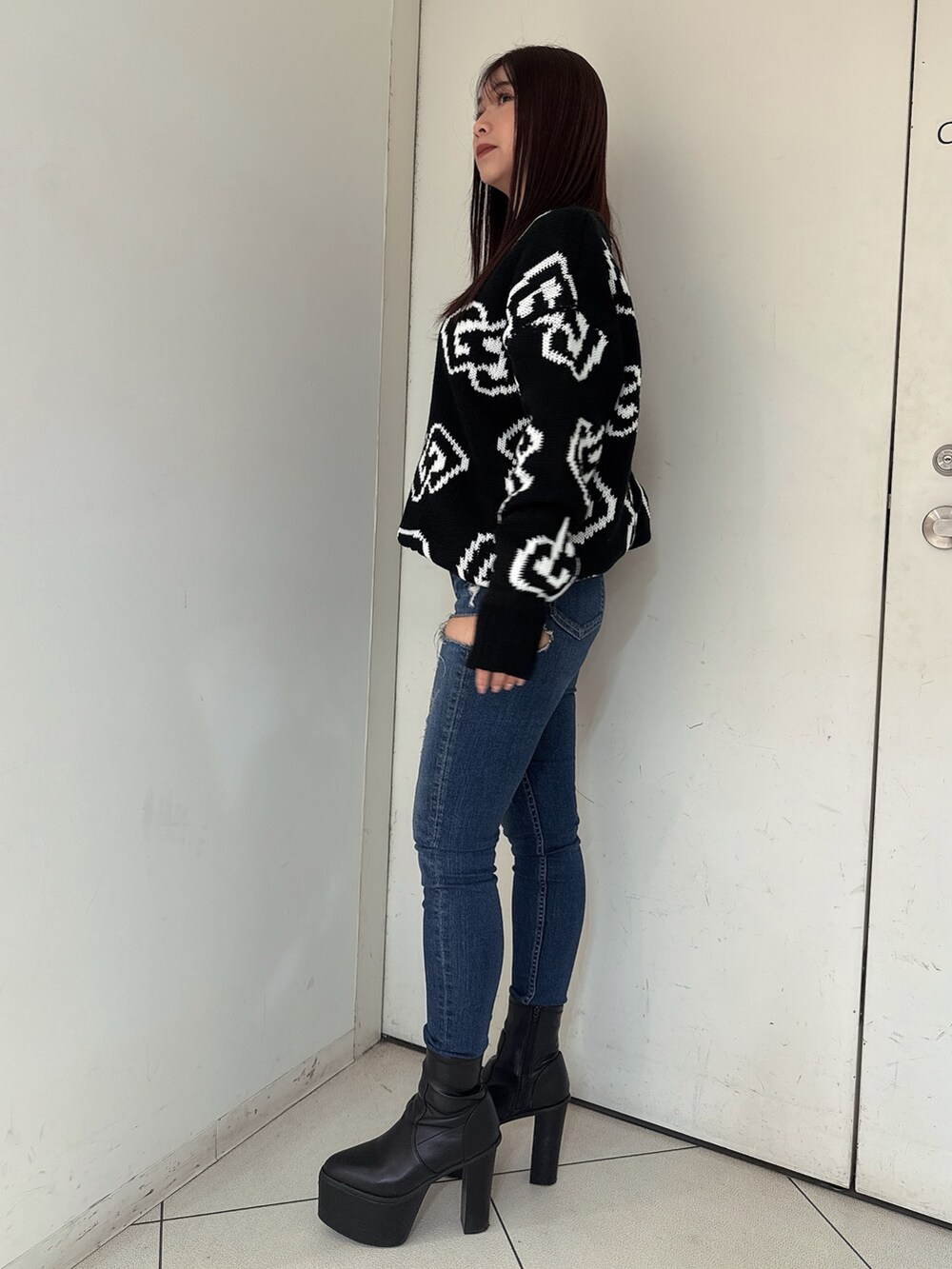 ブラック系のブーツ、ブルー系のデニムパンツ、ブラック系のニット/セーターを着用したレディースの秋コーディネートの2枚目の写真