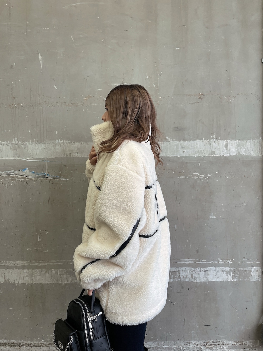 ホワイト系のブルゾン、ホワイト系のニット/セーター、ブルー系のデニムパンツを着用したレディースの冬コーディネートの5枚目の写真