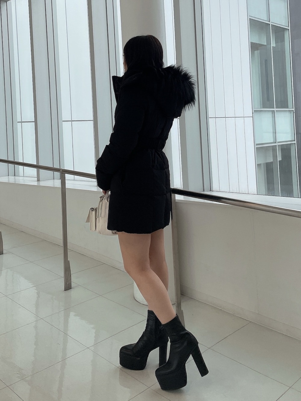 ブラック系のダウンジャケット/コート、ブラック系のワンピース、ホワイト系のバックパック/リュックを着用したレディースの冬コーディネートの3枚目の写真