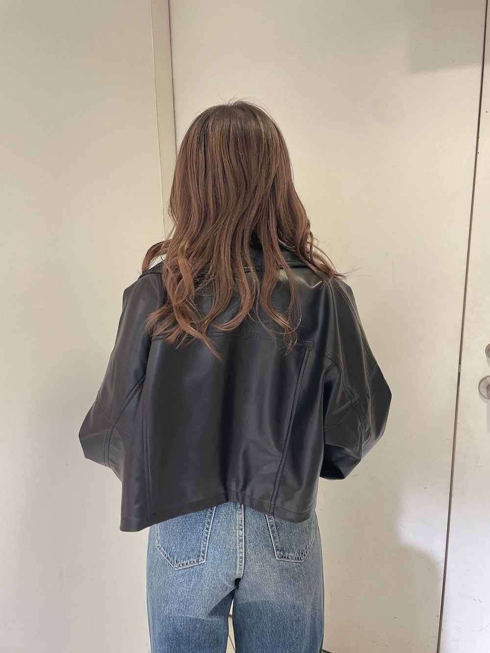 ブルー系のデニムパンツ、ブラック系のライダースジャケット、ホワイト系のタンクトップを着用したレディースの冬コーディネートの4枚目の写真