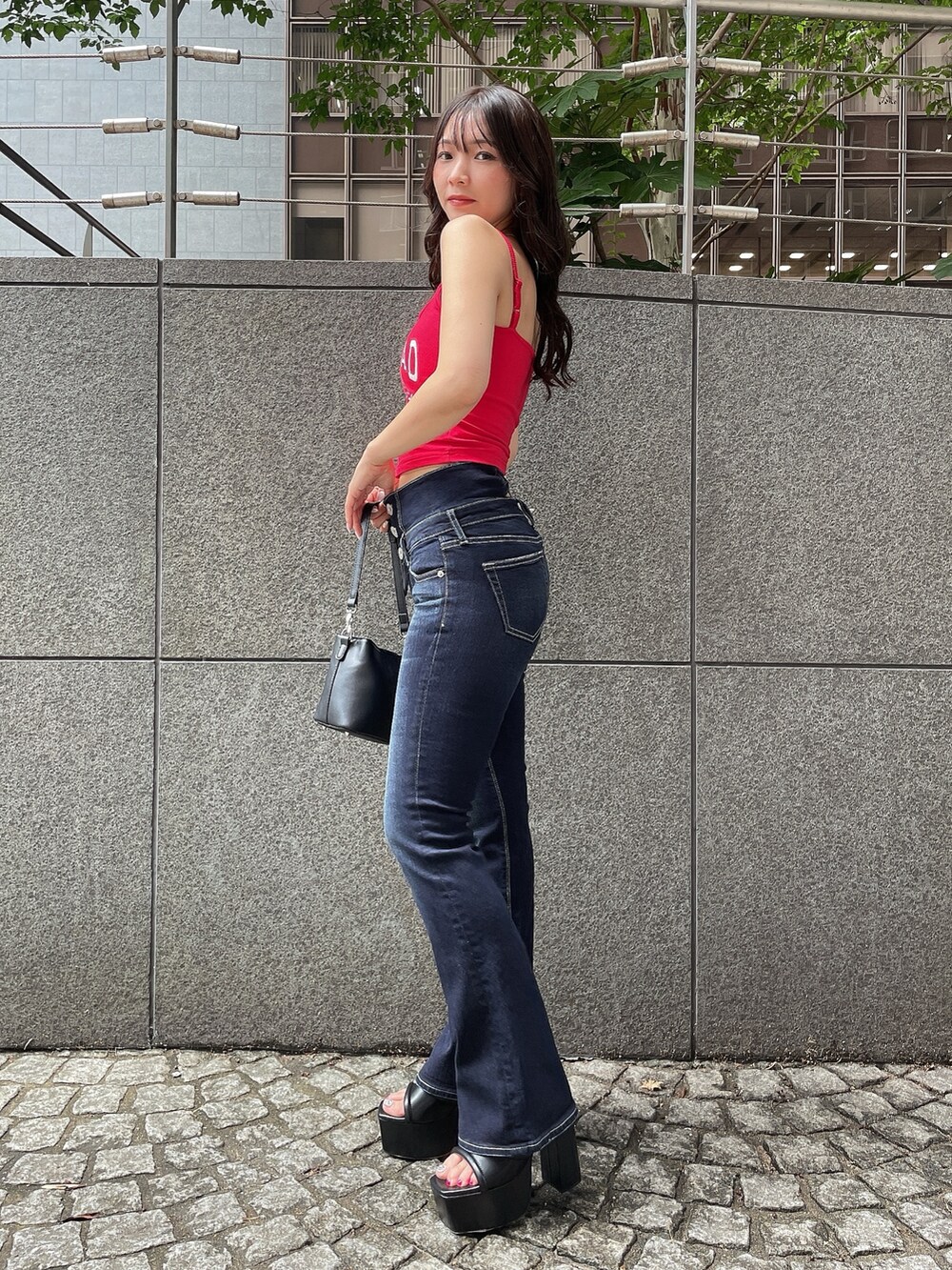 レッド系のキャミソール、ブルー系のデニムパンツ、ブラック系のショルダーバッグを着用したレディースの夏コーディネートの2枚目の写真