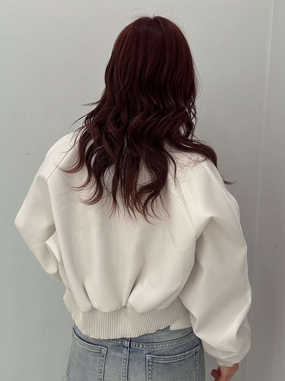 ホワイト系のブルゾン、ブラック系のニット/セーター、ブルー系のデニムパンツを着用したレディースの冬コーディネートの6枚目の写真