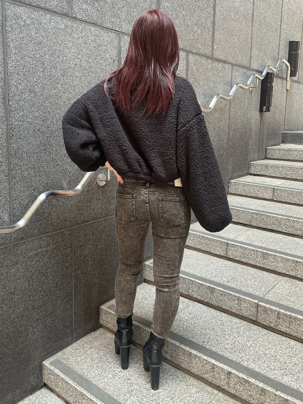 ブラック系のパーカー、ブラック系のデニムパンツ、ブラック系のブーツを着用したレディースの秋コーディネートの3枚目の写真