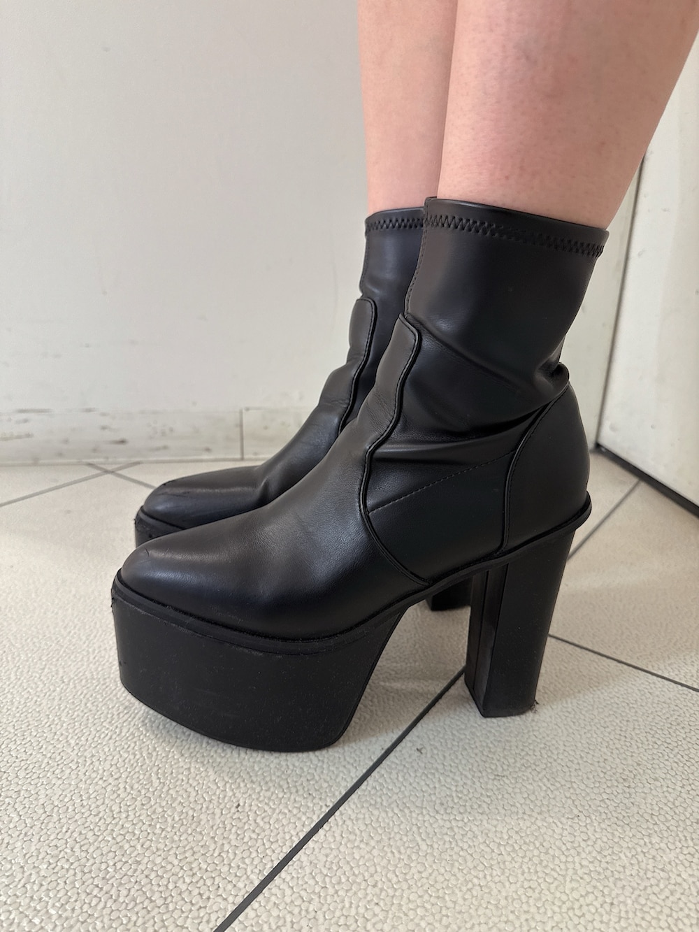 グレー系のニット/セーター、グレー系のスカート、ブラック系のブーツを着用したレディースの秋コーディネートの9枚目の写真