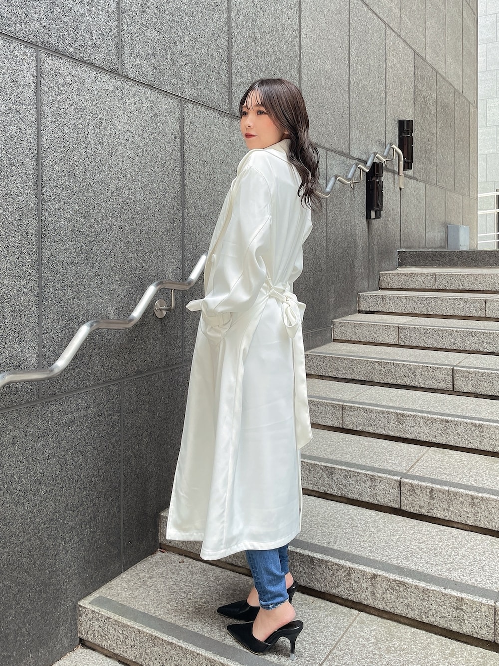 ホワイト系のトレンチコート、ブラック系のTシャツ/カットソー、ブルー系のデニムパンツを着用したレディースの春コーディネートの2枚目の写真