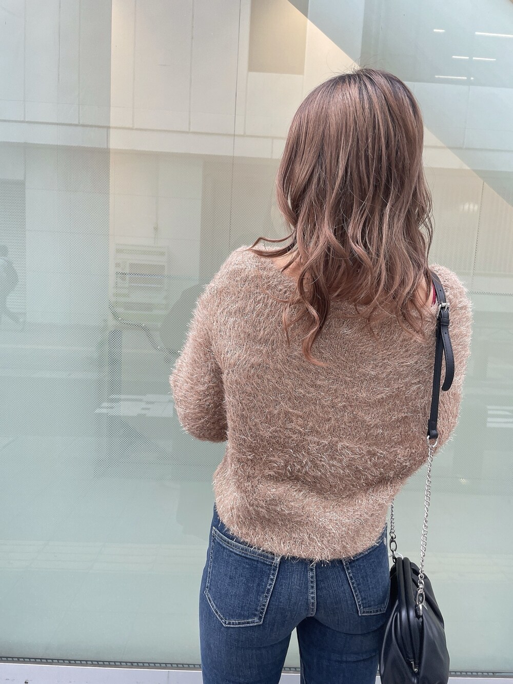 ブラック系のダウンジャケット/コート、ベージュ系のニット/セーター、ブルー系のデニムパンツを着用したレディースの秋コーディネートの6枚目の写真