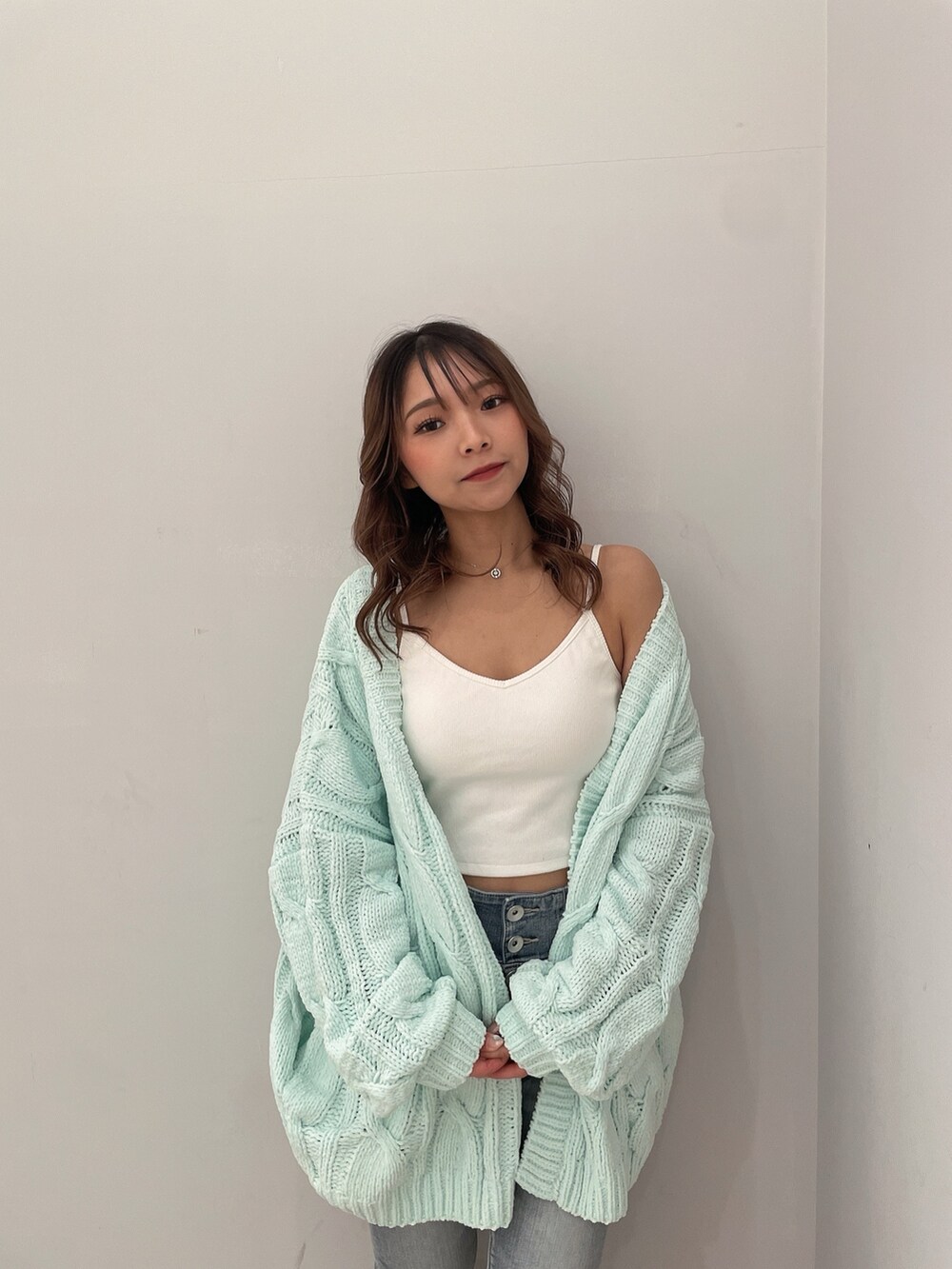 ホワイト系のキャミソール、ブルー系のデニムパンツ、グリーン系のカーディガン/ボレロを着用したレディースの冬コーディネートの5枚目の写真