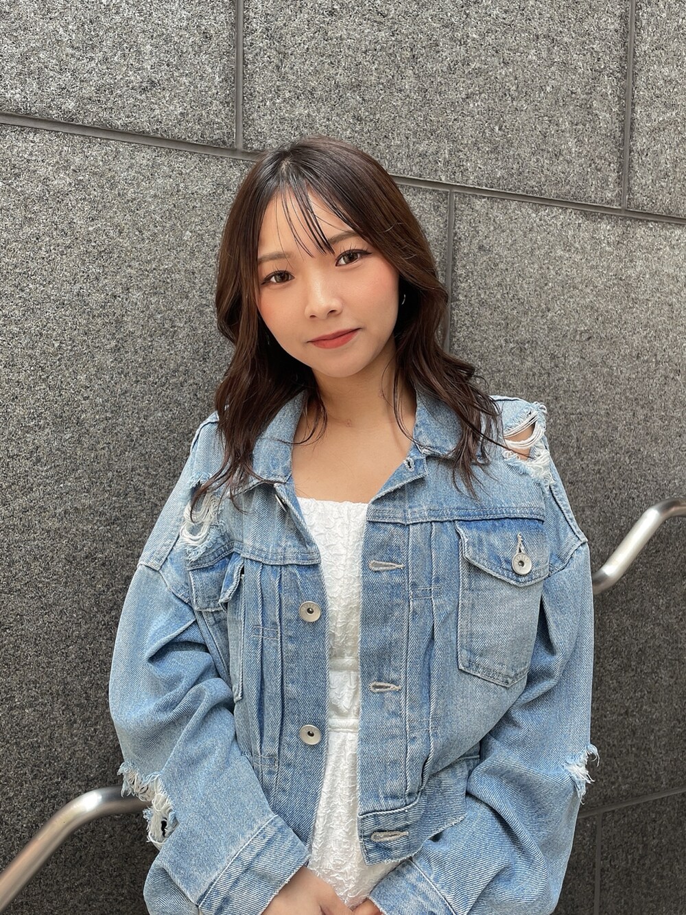 ブルー系のデニムジャケット、ホワイト系のサンダル、ホワイト系のハンドバッグを着用したレディースの春コーディネートの5枚目の写真