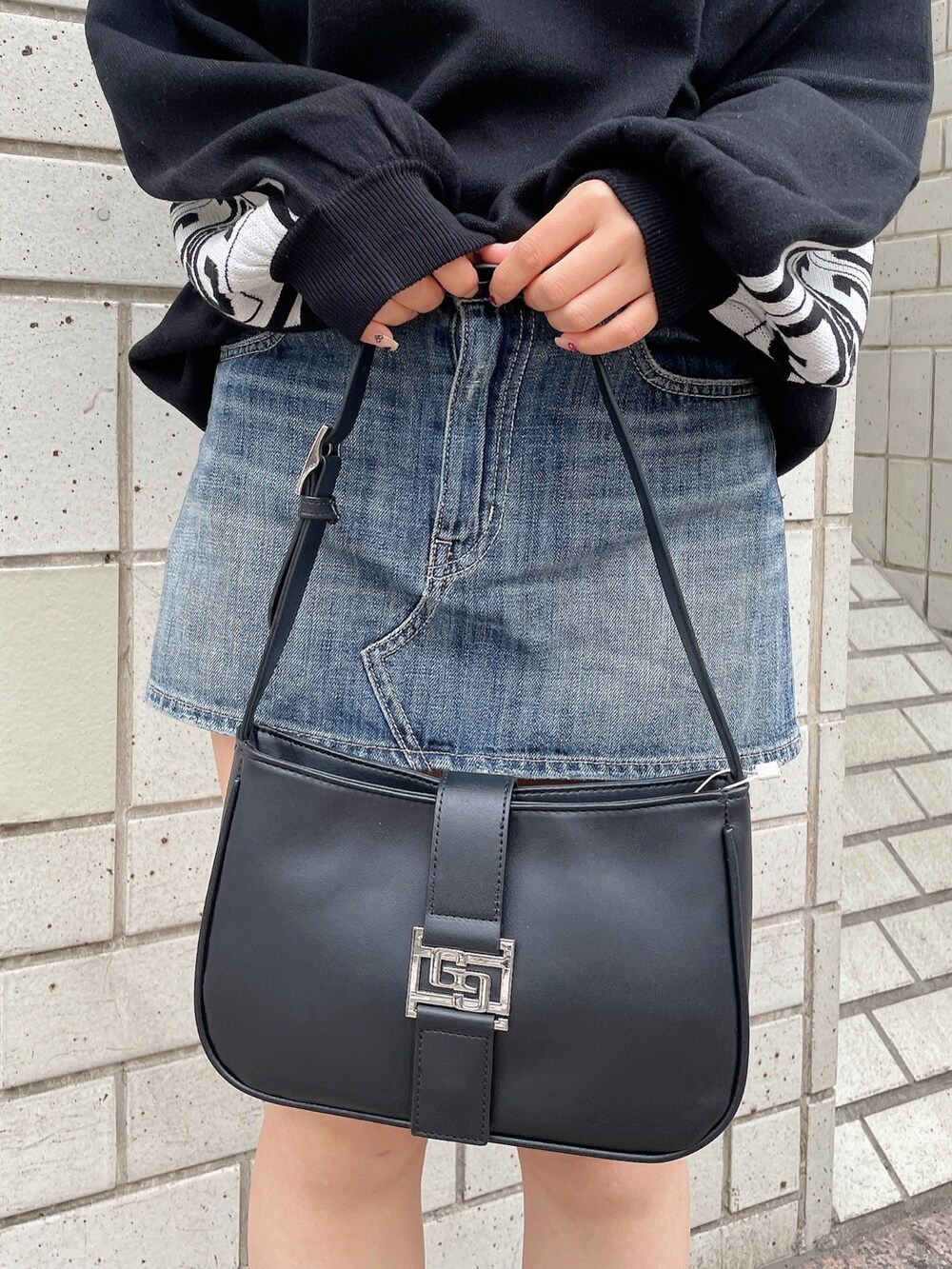 ブラック系のニット/セーター、ブルー系のデニムスカート、ブラック系のハンドバッグを着用したレディースの冬コーディネートの7枚目の写真