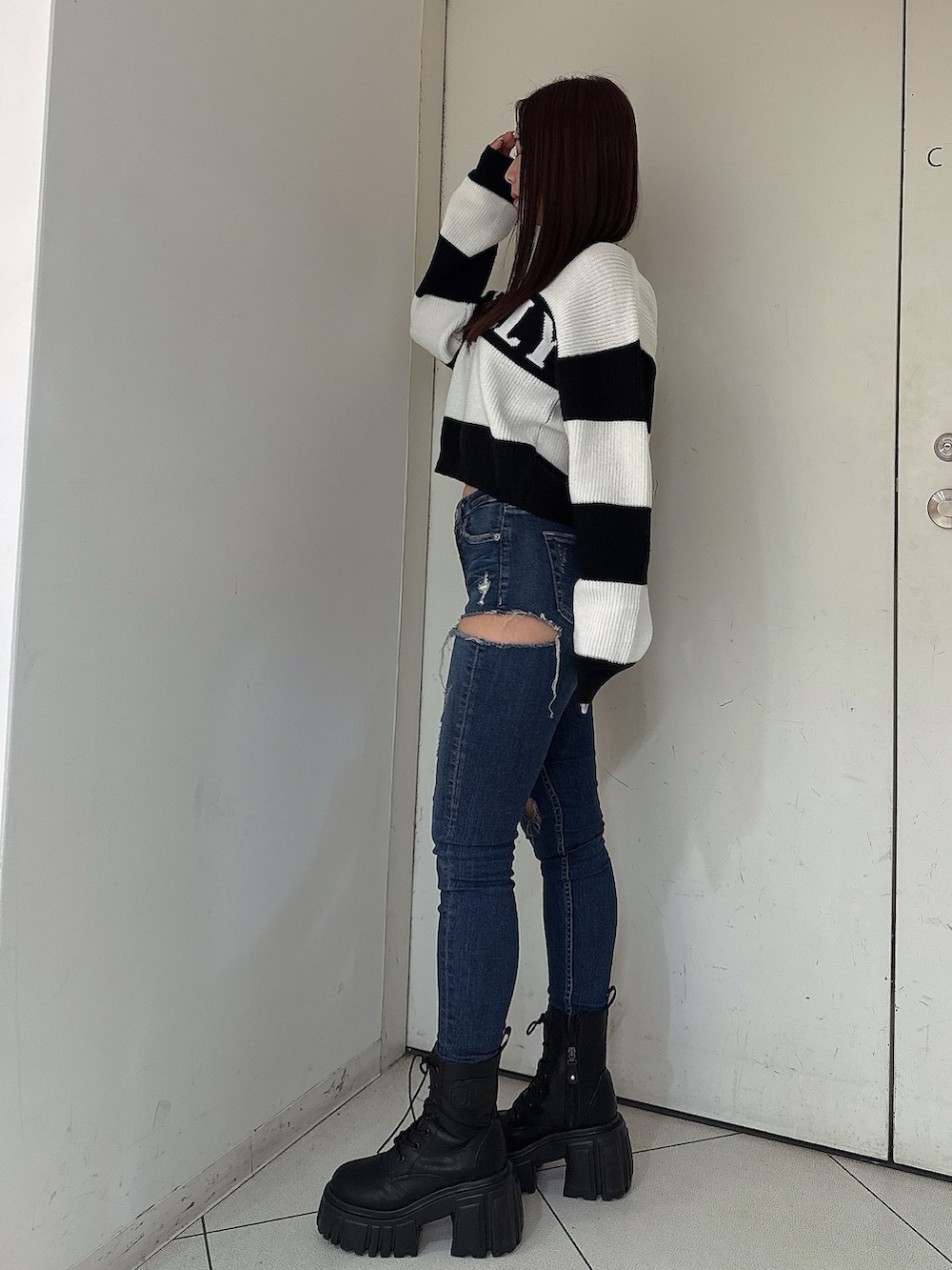 ブルー系のデニムパンツ、ブラック系のブーツ、ブラック系のニット/セーターを着用したレディースの秋コーディネートの2枚目の写真