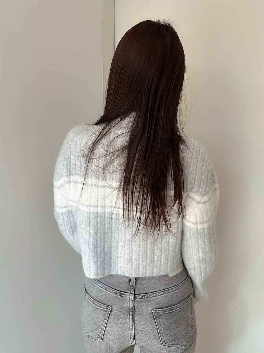 グレー系のデニムパンツ、ブラック系のブーツ、グレー系のニット/セーターを着用したレディースの冬コーディネートの6枚目の写真