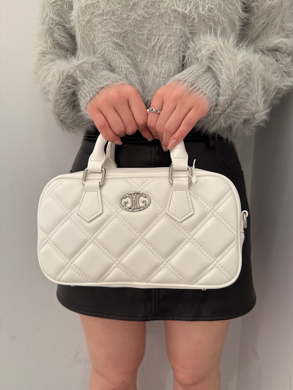 ブラック系のブーツ、ブラック系のスカート、ホワイト系のハンドバッグを着用したレディースの冬コーディネートの9枚目の写真