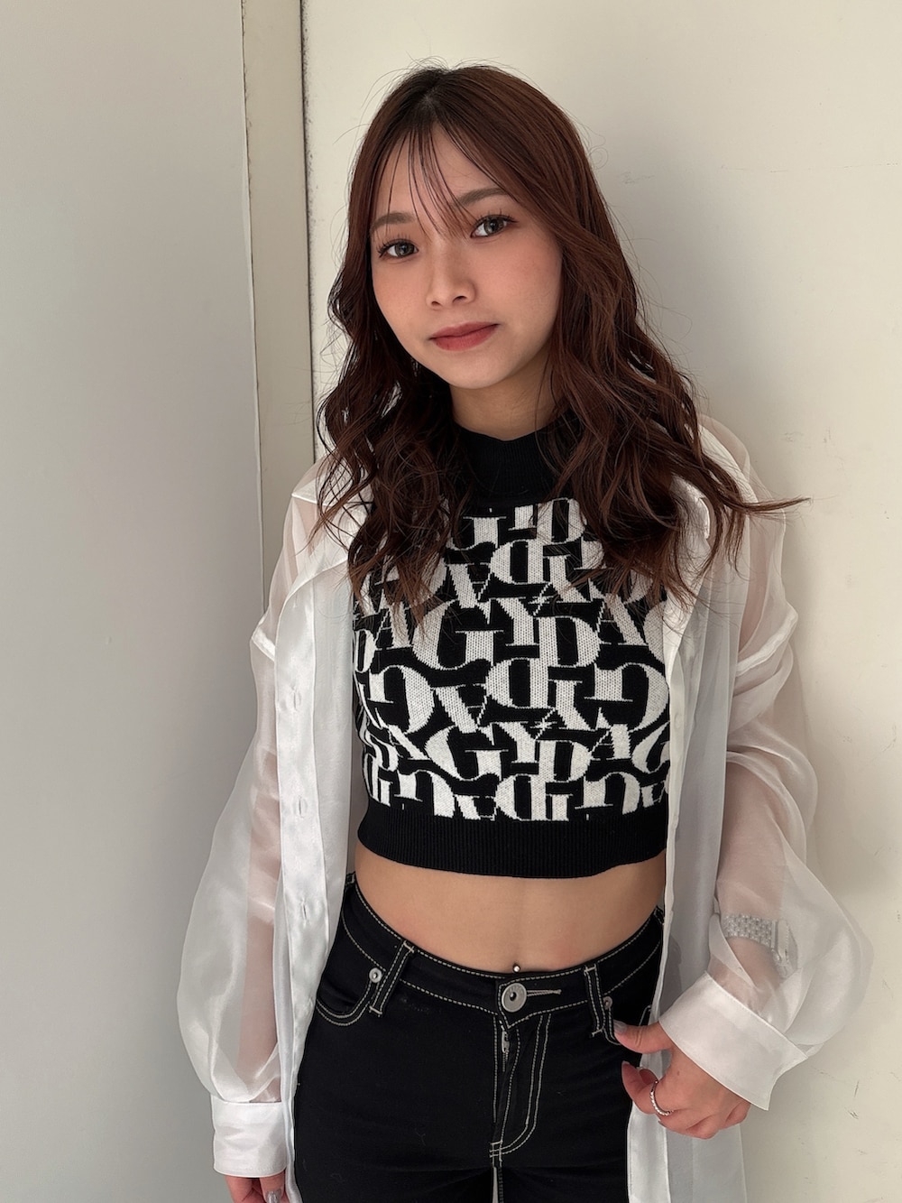 ブラック系のニット/セーター、ブラック系のデニムパンツ、ホワイト系のシャツ/ブラウスを着用したレディースの春コーディネートの4枚目の写真