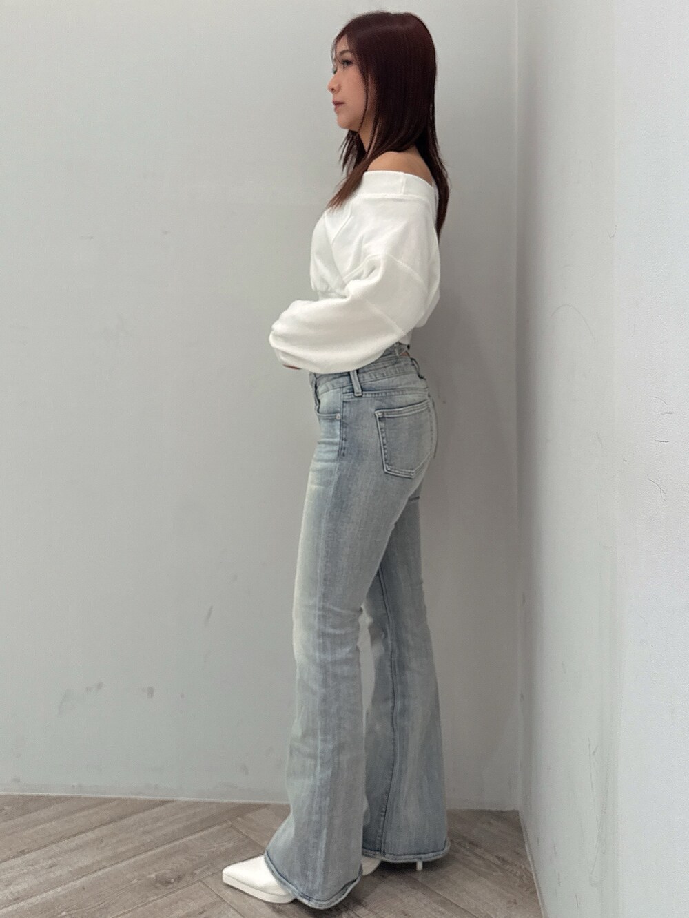 ブルー系のデニムパンツ、ホワイト系のパンプス、ホワイト系のスウェットを着用したレディースの冬コーディネートの2枚目の写真