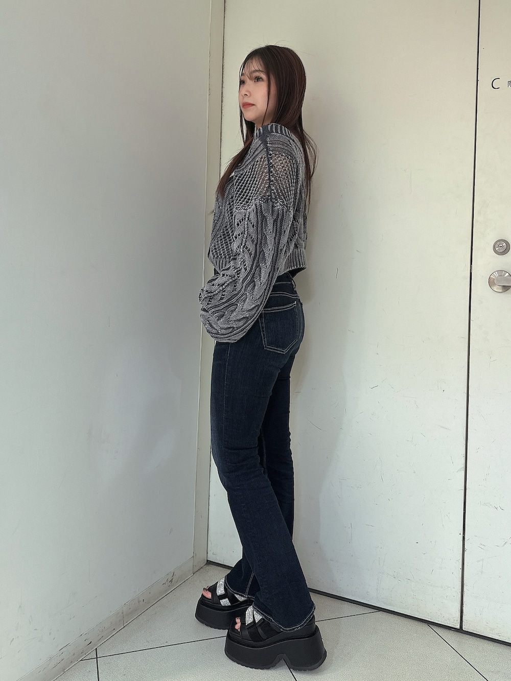 ブルー系のデニムパンツ、ブルー系のニット/セーター、ブラック系のサンダルを着用したレディースの春コーディネートの2枚目の写真