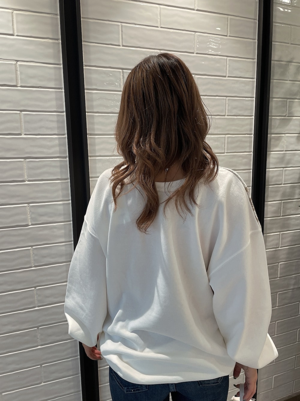 ホワイト系のTシャツ/カットソー、ホワイト系のバックパック/リュック、ブルー系のデニムパンツを着用したレディースの冬コーディネートの5枚目の写真