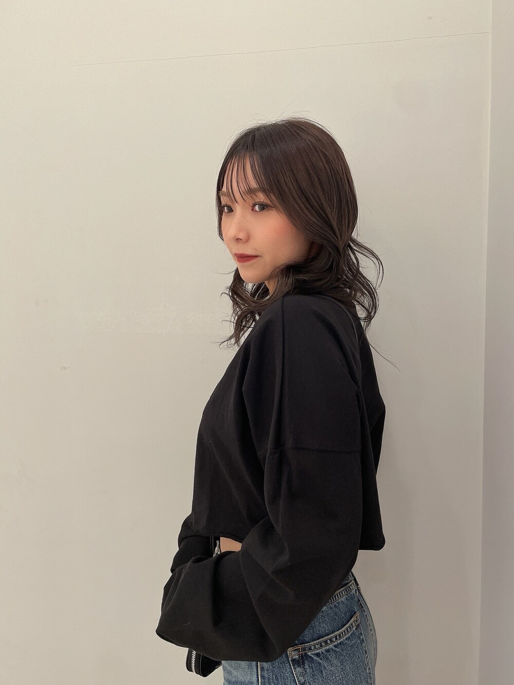 ブラック系のTシャツ/カットソー、ブルー系のデニムパンツ、ブラック系のブーツを着用したレディースの春コーディネートの5枚目の写真