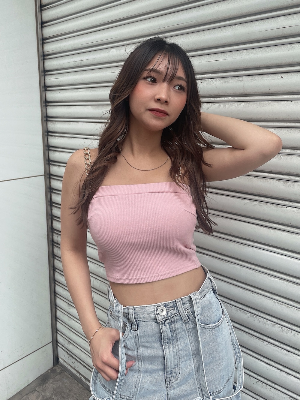 ピンク系のキャミソール、ブルー系のデニムパンツ、ホワイト系のスニーカーを着用したレディースの夏コーディネートの4枚目の写真