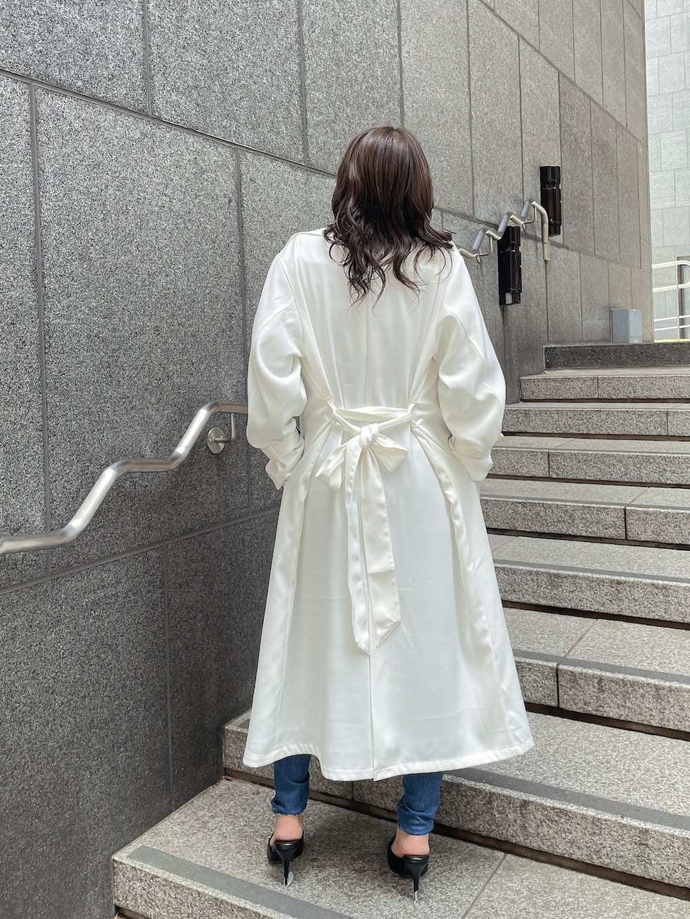 ホワイト系のトレンチコート、ブラック系のTシャツ/カットソー、ブルー系のデニムパンツを着用したレディースの春コーディネートの3枚目の写真